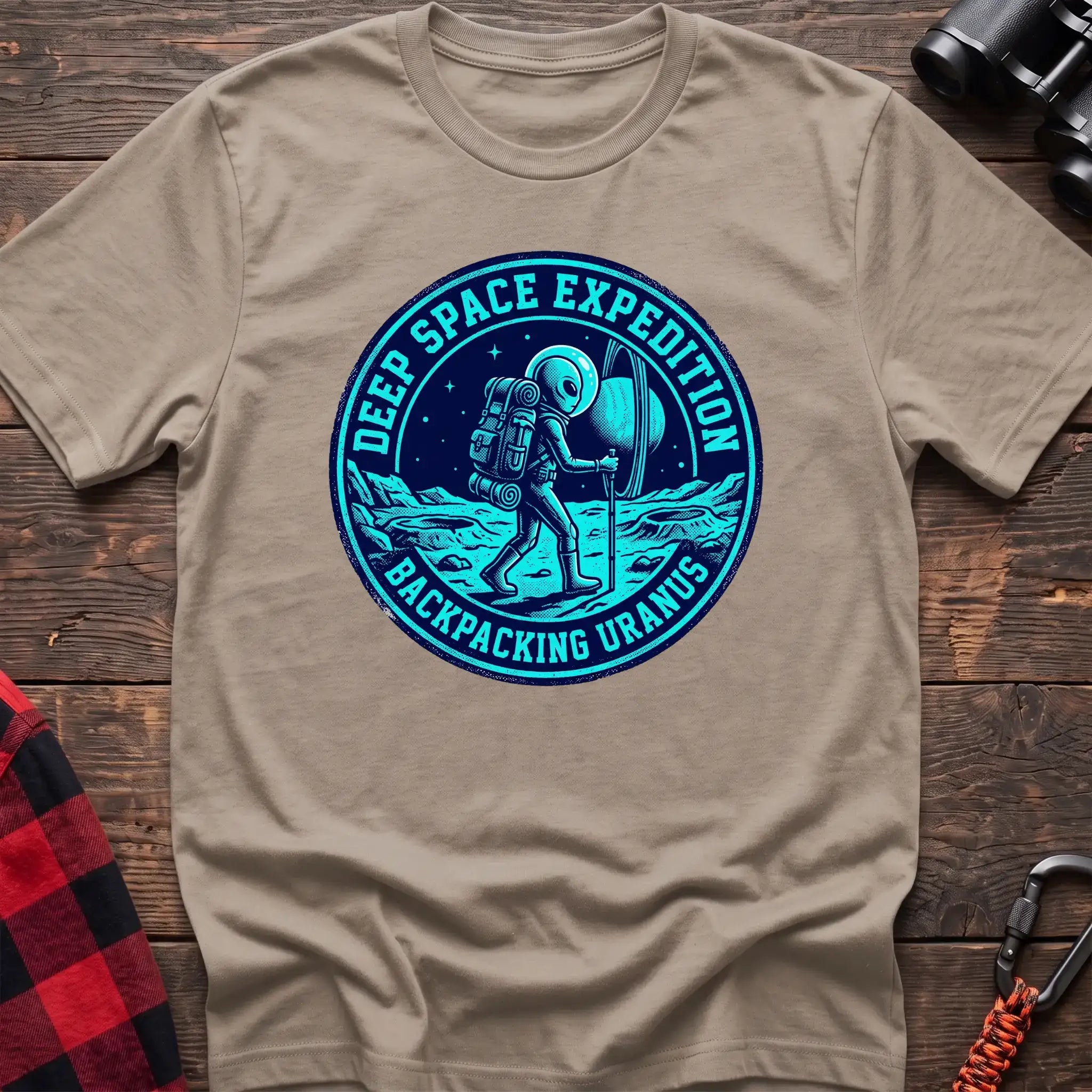 Sand t-shirt with circular badge graphic of an alien backpacking on Uranus, reading Deep Space Expedition Backpacking Uranus