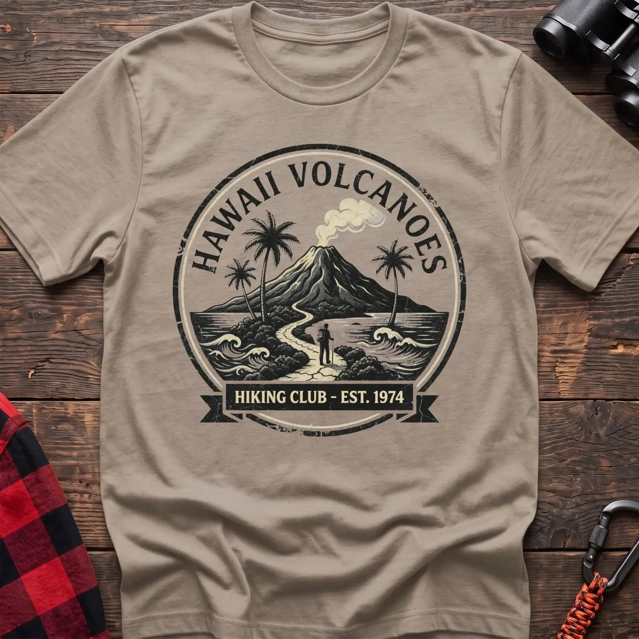 Sand t-shirt with circular Hawaii Volcanoes badge graphic showing a volcano, palm trees, and a hiker, reading Hiking Club Est 1974