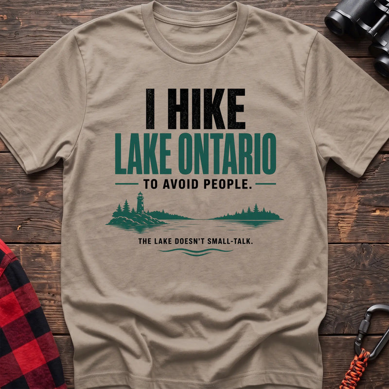 Sand cotton hiking t-shirt with lighthouse and lake graphic and "I hike Lake Ontario to avoid people – the lake doesn't small-talk" quote