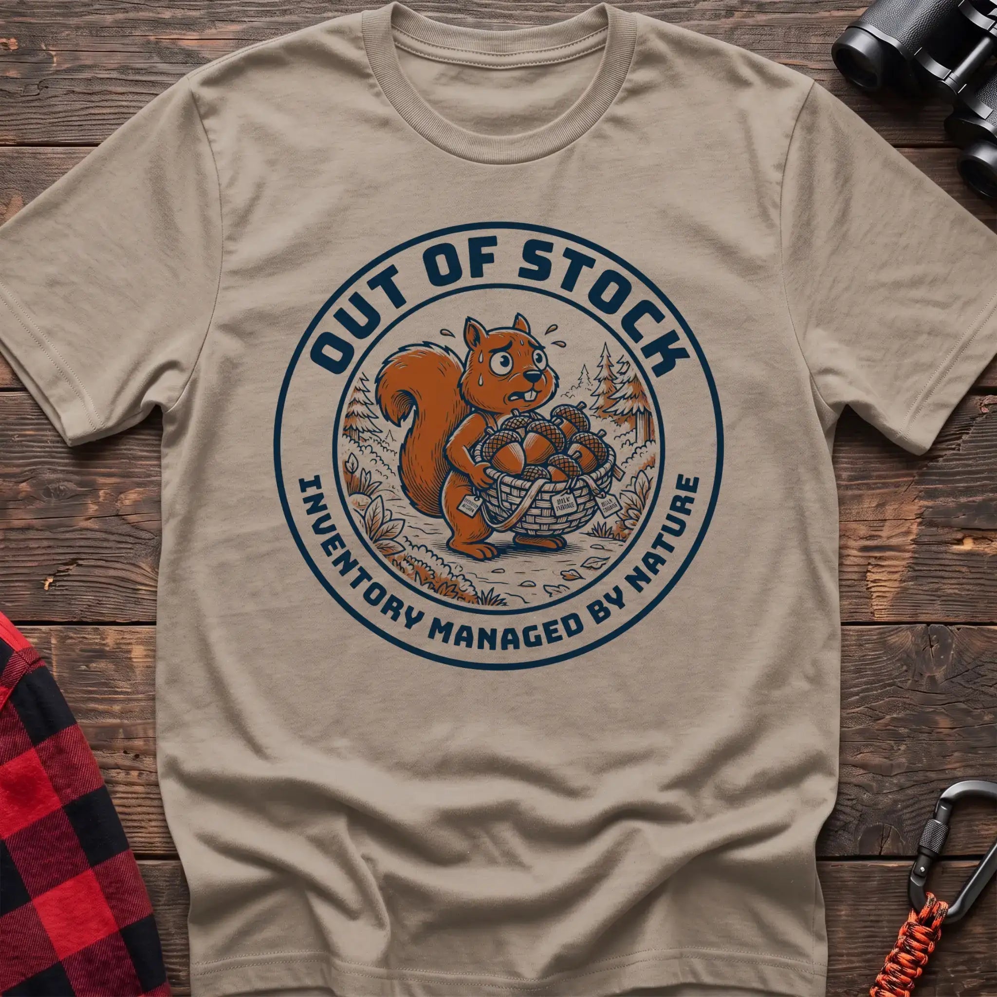 Sand t-shirt with circular graphic of a stressed squirrel holding a basket of acorns, reading Out of Stock Inventory Managed by Nature