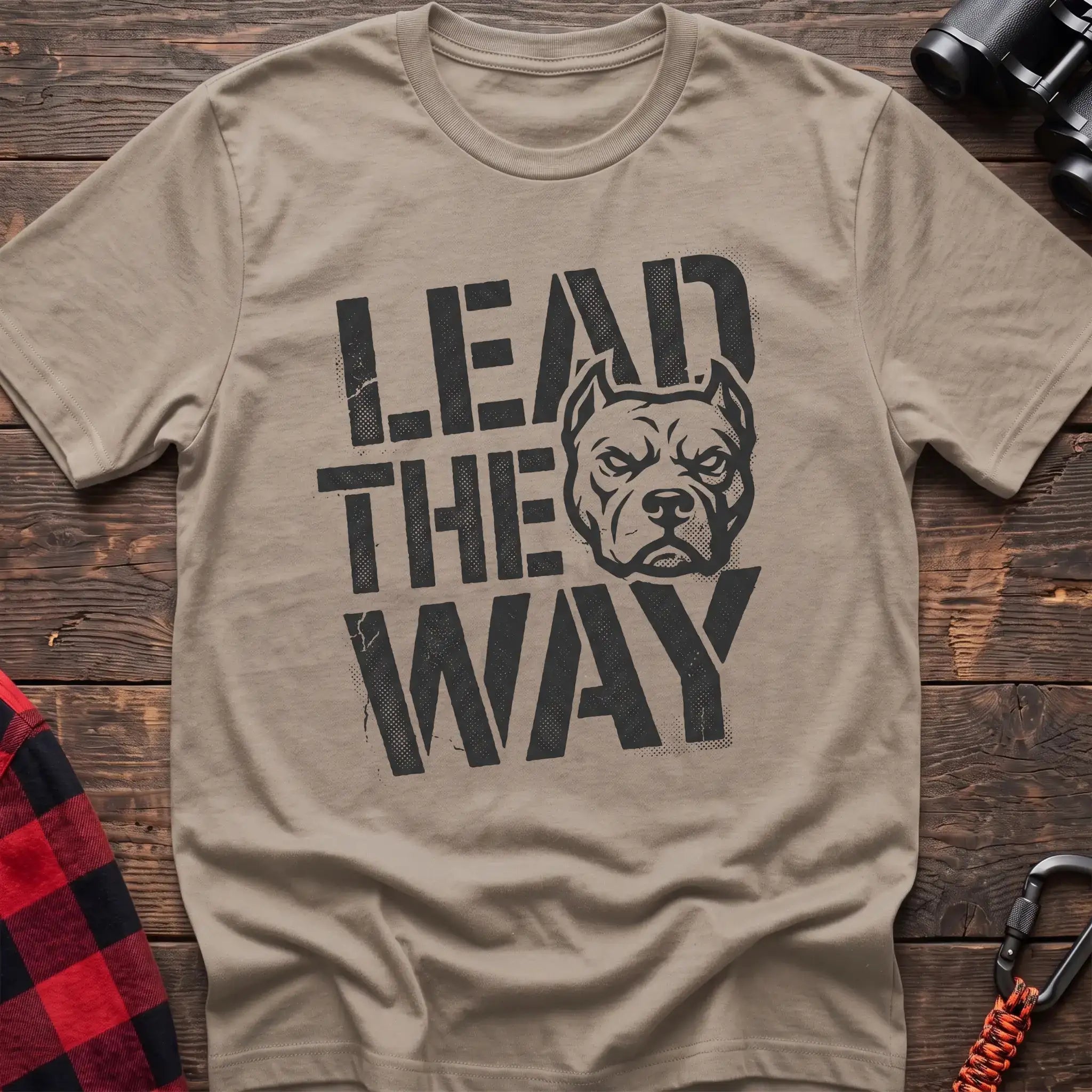 Sand t-shirt with a distressed graphic of a stern pit bull head integrated into the bold text “LEAD THE WAY,” laid flat on a wooden surface.