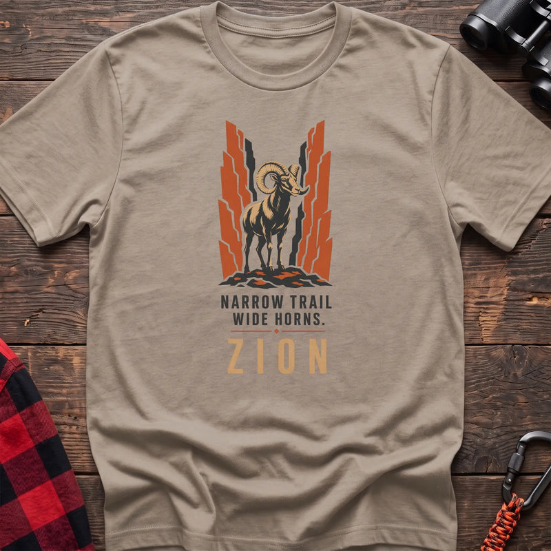 Sand cotton t-shirt with a bighorn sheep graphic and Narrow Trail Wide Horns Zion text on rustic wood