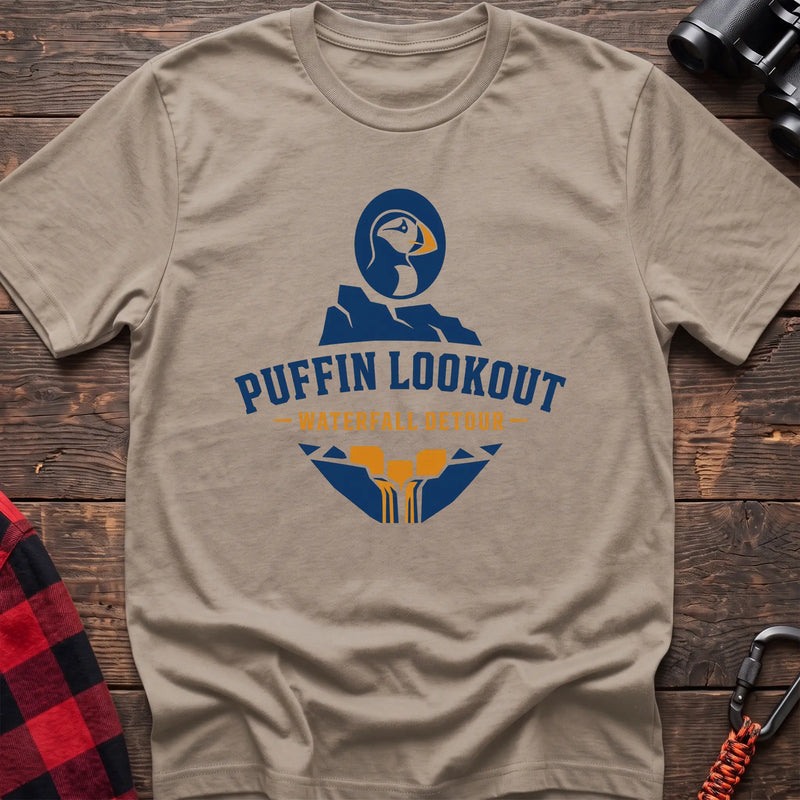 Sand cotton t-shirt with a puffin and waterfall graphic and Puffin Lookout Waterfall Detour text on rustic wood