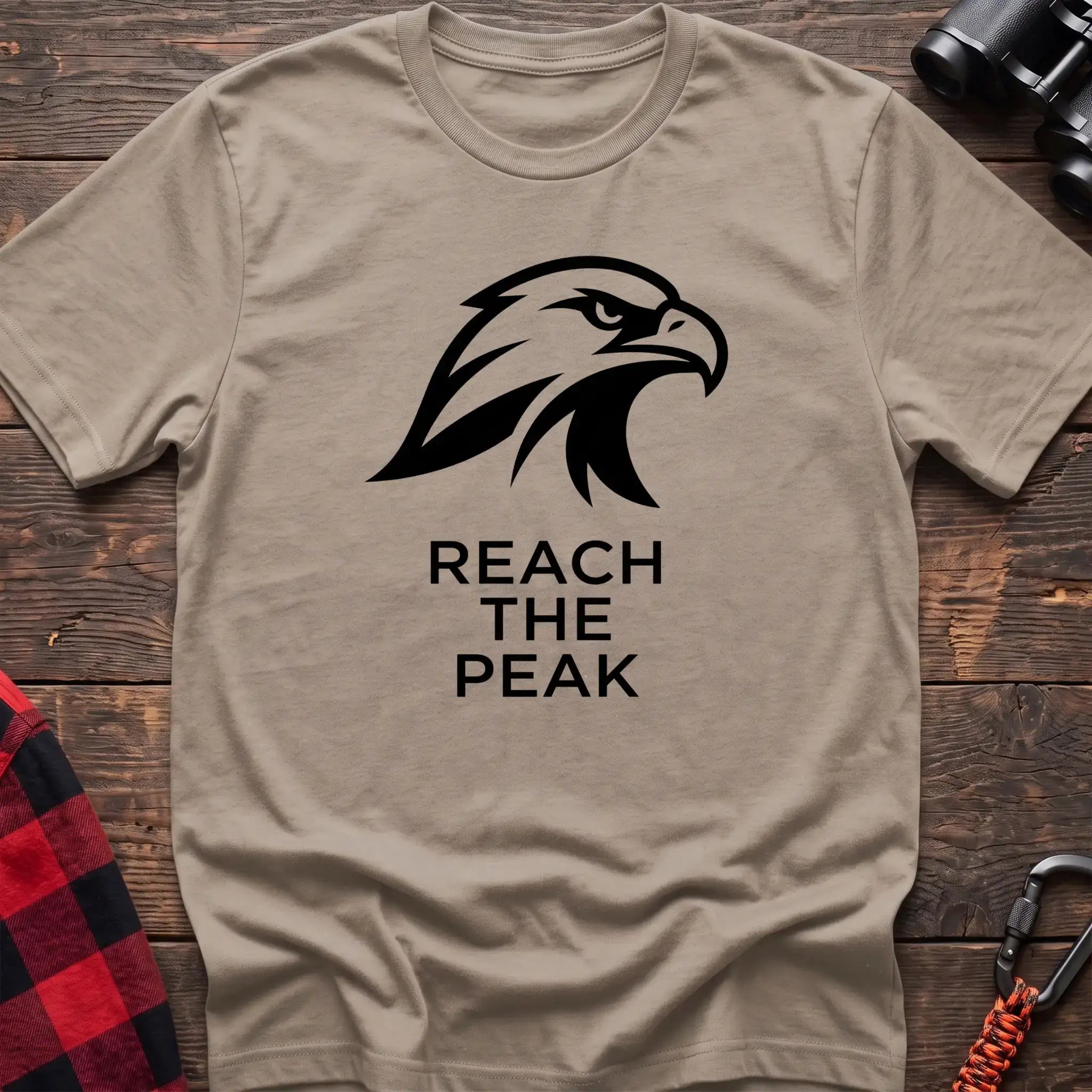 Sand crew-neck t-shirt with a black stylized eagle head logo and the text “REACH THE PEAK” printed on the front