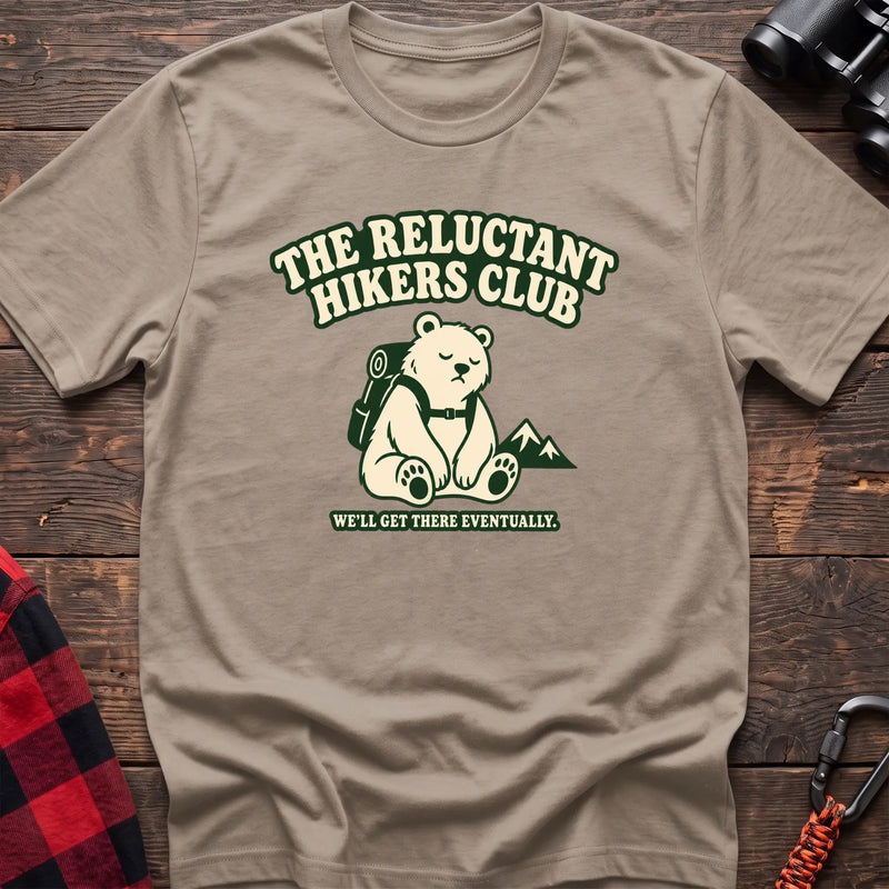 Sand cotton t-shirt with a sitting backpack bear graphic and The Reluctant Hikers Club text on rustic wood