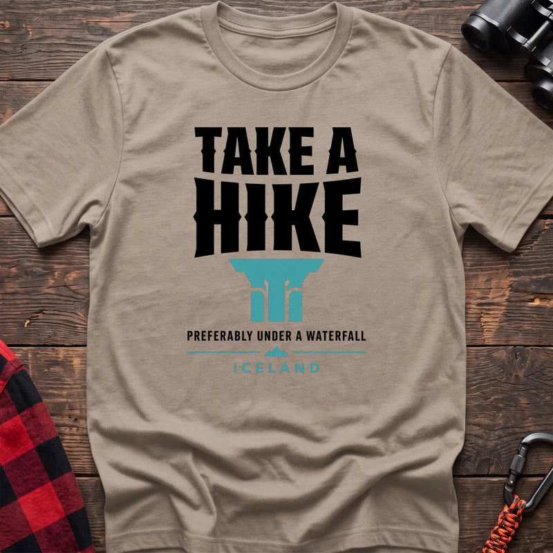 Sand cotton t-shirt with a waterfall graphic and Take a Hike Preferably Under a Waterfall Iceland text on rustic wood