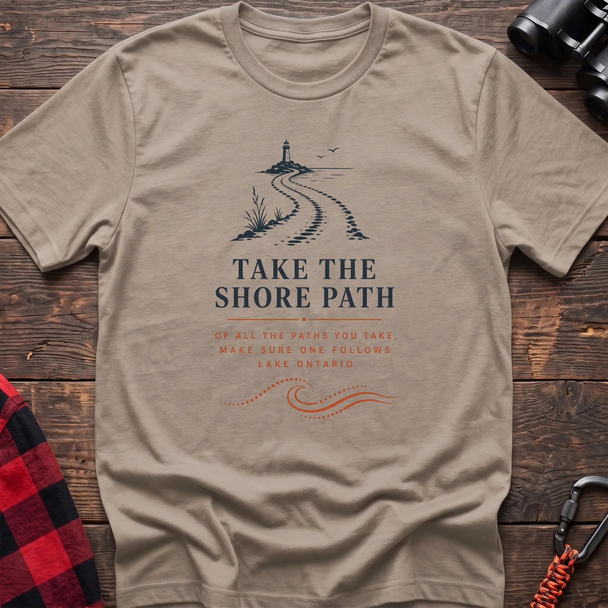 Sand cotton hiking t-shirt with lighthouse and winding shore path graphic and "Take the Shore Path – make sure one follows Lake Ontario" quote