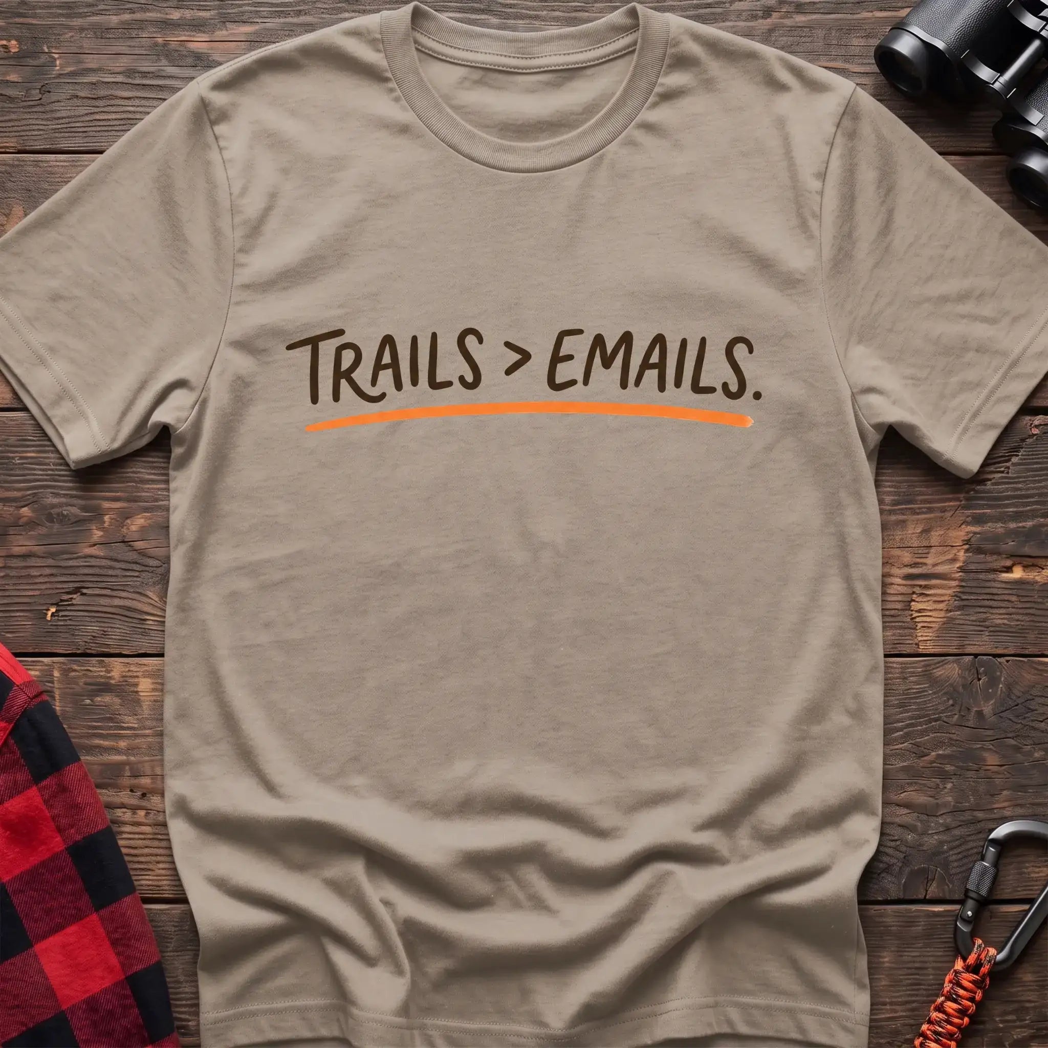 Sand t-shirt with brown handwritten-style text reading Trails greater than Emails and an orange underline
