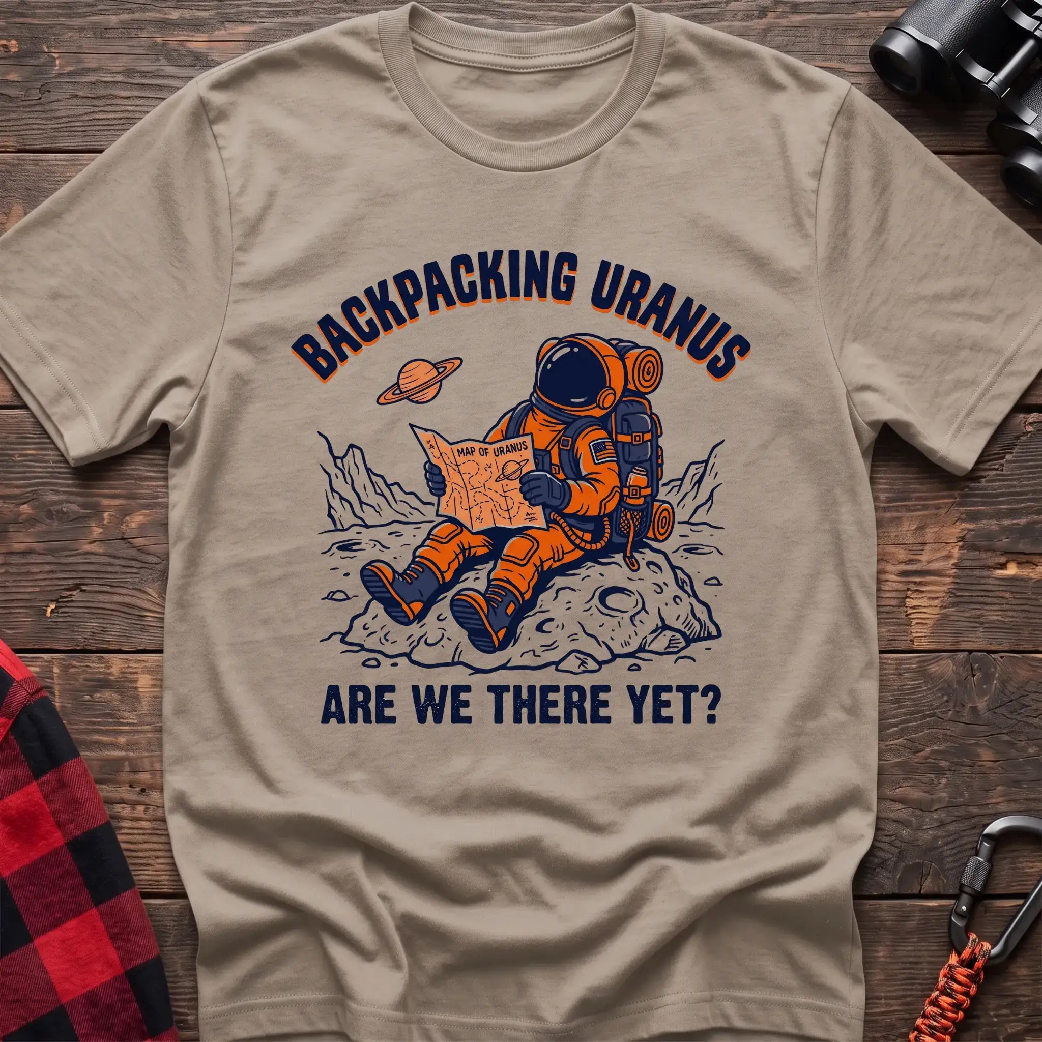 Sand t-shirt with astronaut sitting on a rock reading a Map of Uranus and the text Backpacking Uranus Are We There Yet
