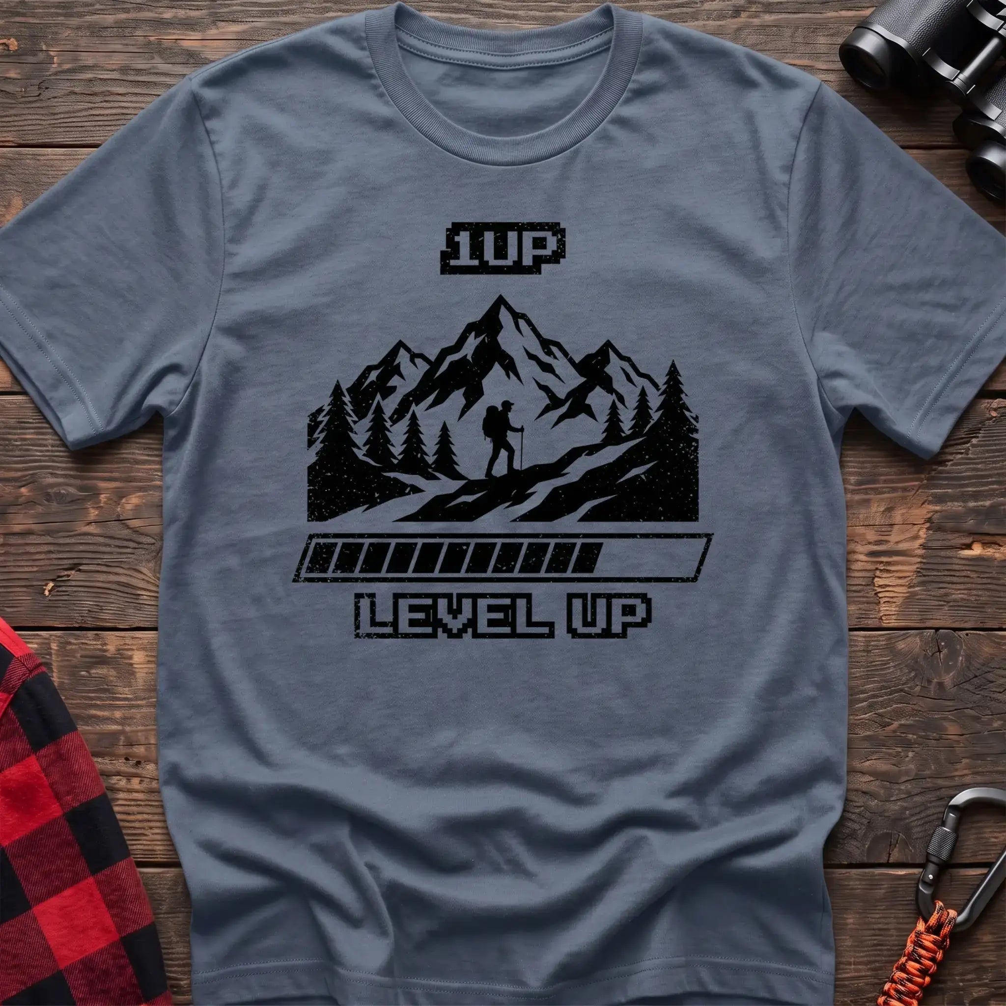 Stone blue t-shirt with black graphic of a hiker on a mountain trail under pixel-style 1UP text and a progress bar reading Level Up