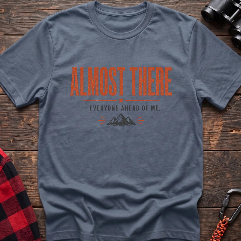 Stone blue cotton t-shirt with a mountain graphic and Almost There Everyone Ahead of Me text on rustic wood