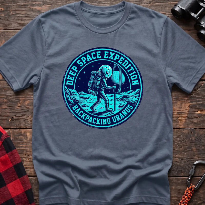 Stone blue t-shirt with circular badge graphic of an alien backpacking on Uranus, reading Deep Space Expedition Backpacking Uranus