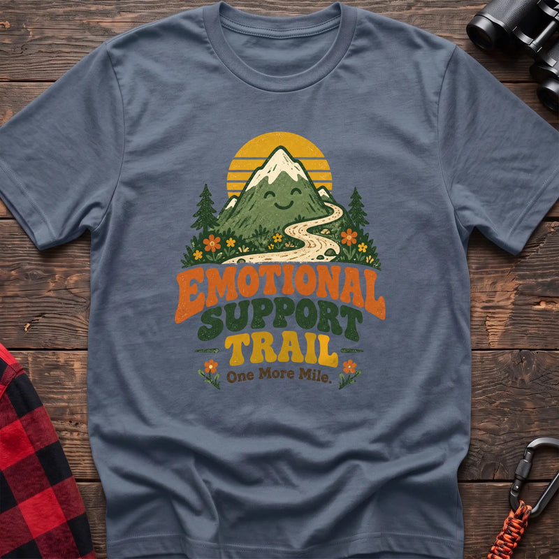 Stone blue cotton t-shirt with a smiling mountain and trail graphic and Emotional Support Trail text on rustic wood