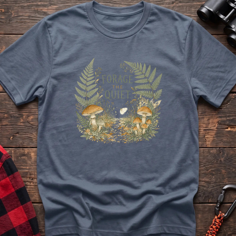 Stone blue cotton t-shirt with a mushroom and fern graphic and Forage the Quiet text on rustic wood
