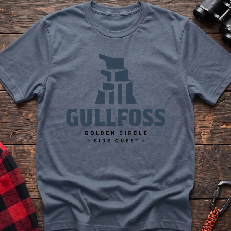 Stone blue cotton t-shirt with a stylized waterfall graphic and Gullfoss Golden Circle Side Quest text on rustic wood