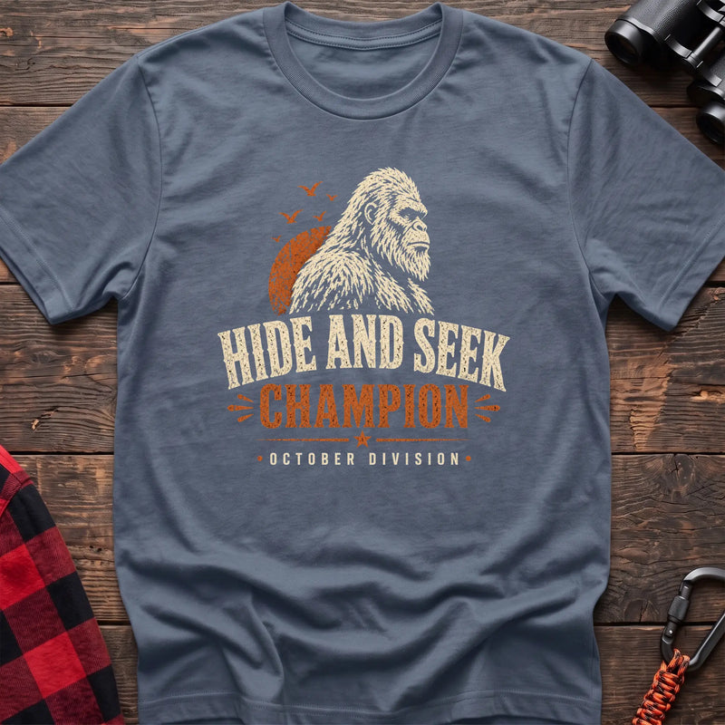 Stone blue cotton t-shirt with a Bigfoot graphic and Hide and Seek Champion October Division text on rustic wood