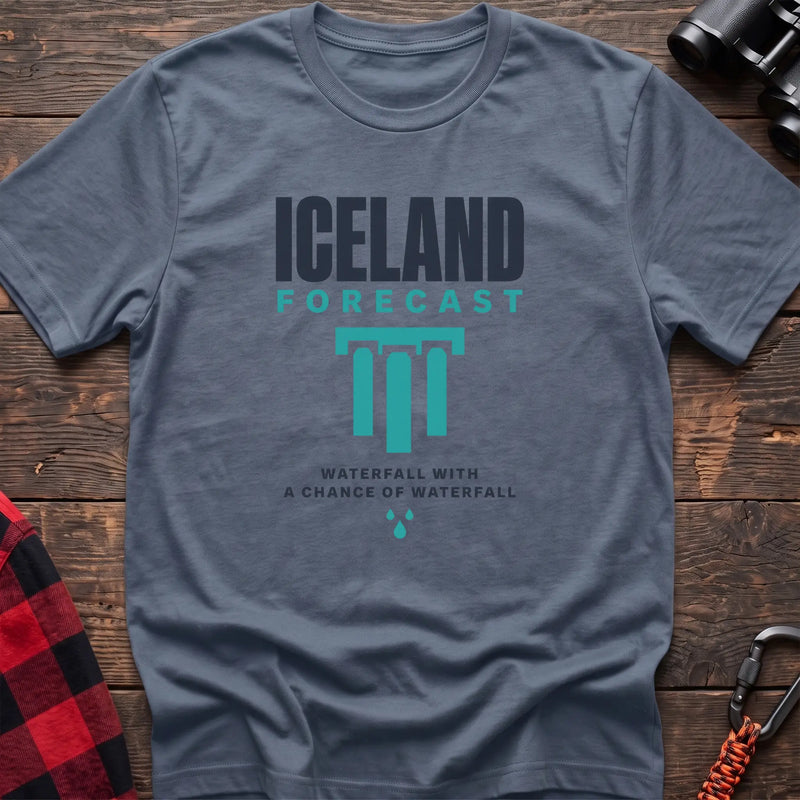 Stone blue cotton t-shirt with an Iceland Forecast graphic and Waterfall with a Chance of Waterfall text on rustic wood