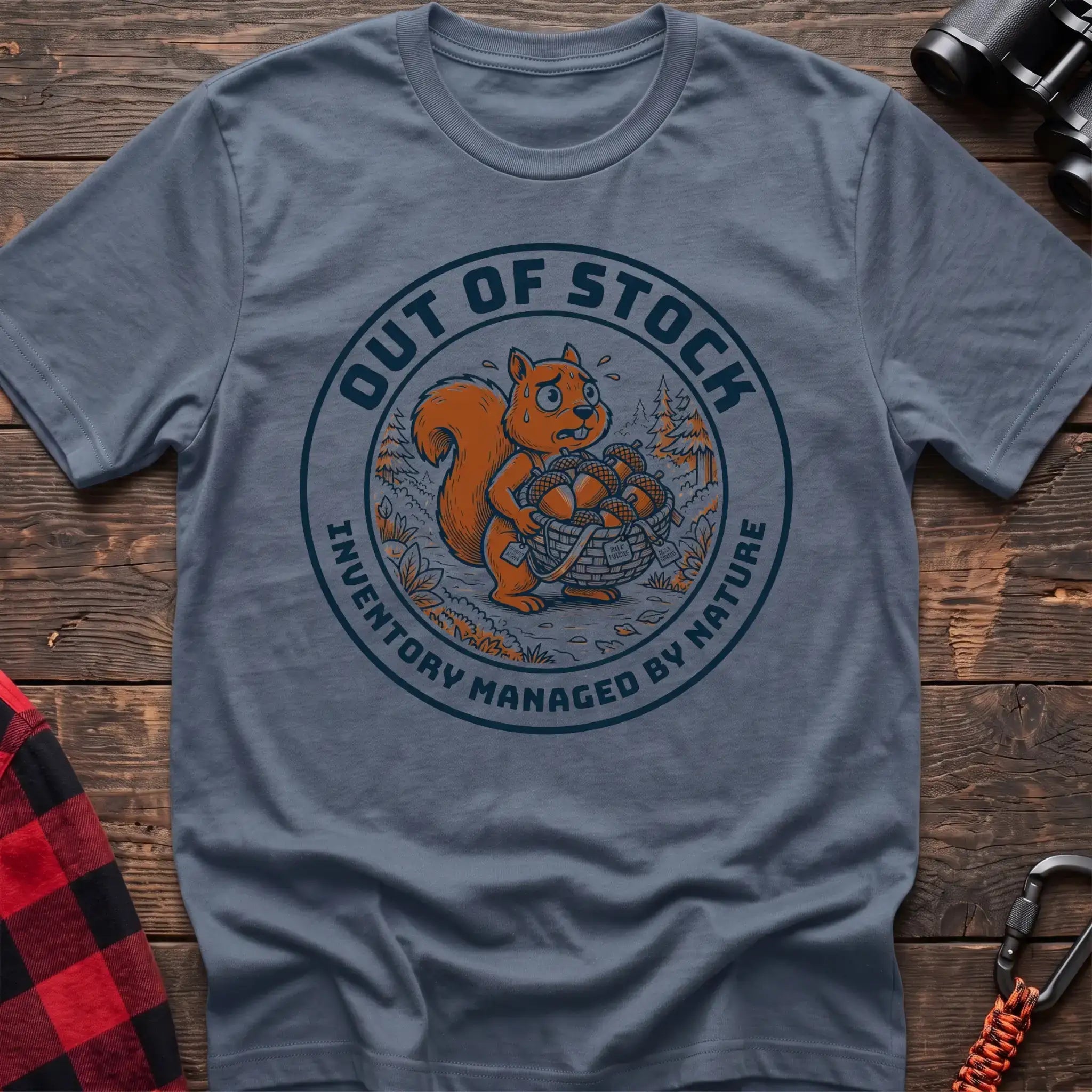 Stone blue t-shirt with circular graphic of a stressed squirrel holding a basket of acorns, reading Out of Stock Inventory Managed by Nature