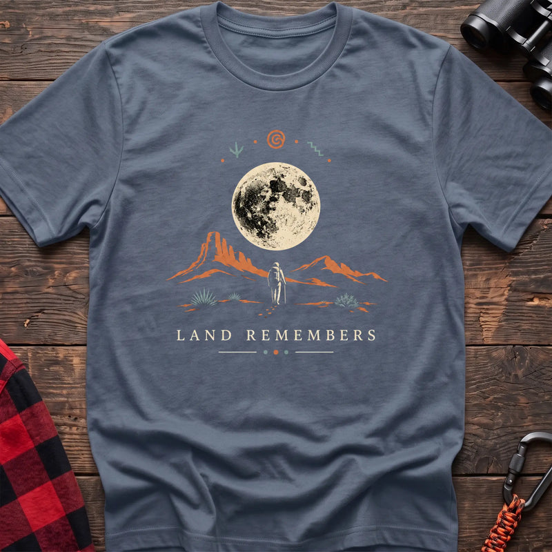 Stone blue cotton t-shirt with a desert hiker and full moon graphic and Land Remembers text on rustic wood