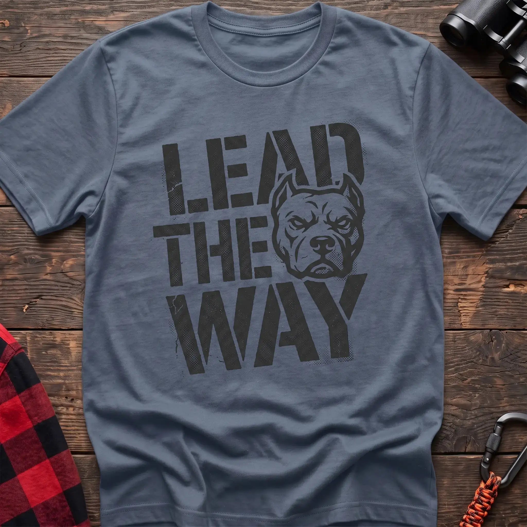 Stone blue t-shirt with a distressed graphic of a stern pit bull head integrated into the bold text “LEAD THE WAY,” laid flat on a wooden surface.