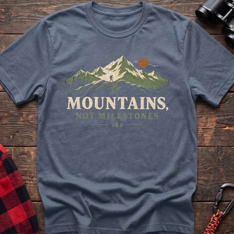 Stone blue cotton t-shirt with a hiker and mountain graphic and Mountains Not Milestones text on rustic wood