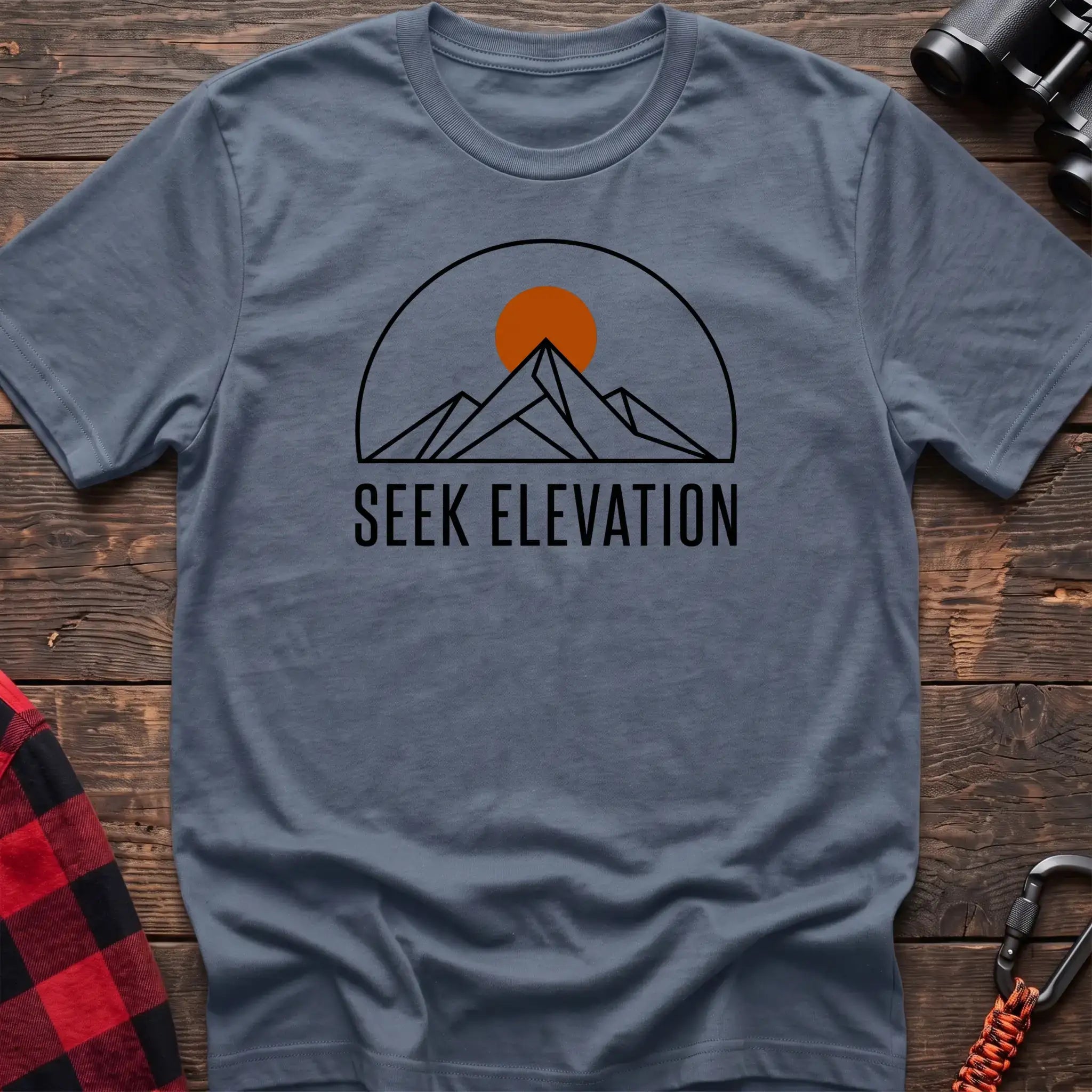 Stone blue t-shirt with minimalist mountain and sun graphic reading Seek Elevation