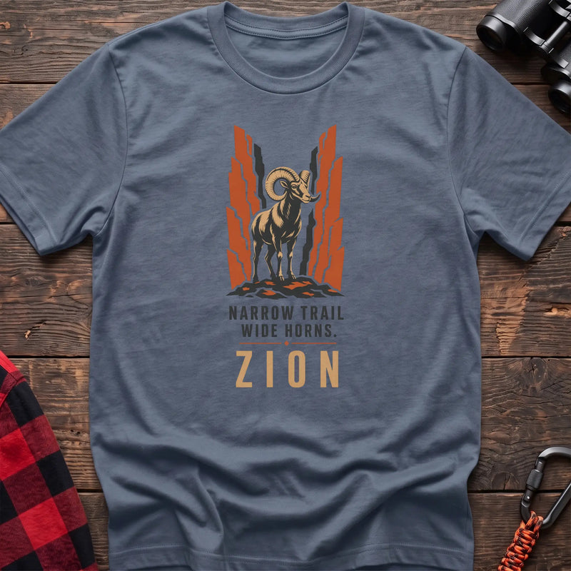 Stone blue cotton t-shirt with a bighorn sheep graphic and Narrow Trail Wide Horns Zion text on rustic wood