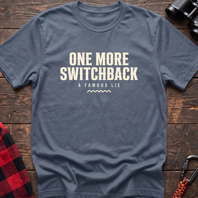 Stone blue cotton t-shirt with One More Switchback A Famous Lie text on rustic wood