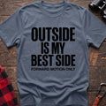 Stone blue t-shirt with bold black text reading “OUTSIDE IS MY BEST SIDE” and “FORWARD MOTION ONLY” below it, laid flat on a wooden surface.