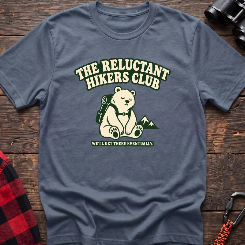 Stone blue cotton t-shirt with a sitting backpack bear graphic and The Reluctant Hikers Club text on rustic wood