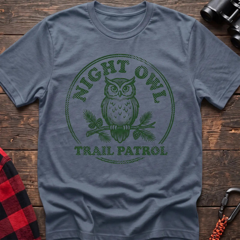 Stone blue t-shirt with green owl on a pine branch graphic and the text Night Owl Trail Patrol