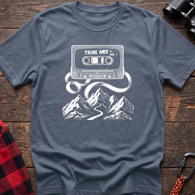 Stone blue t-shirt with white cassette tape graphic labeled Trail Mix Vol. 1, with tape unspooling into a trail through mountains