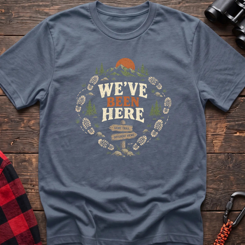 Stone blue cotton t-shirt with a bootprint circle and trail sign graphic and We’ve Been Here text on rustic wood