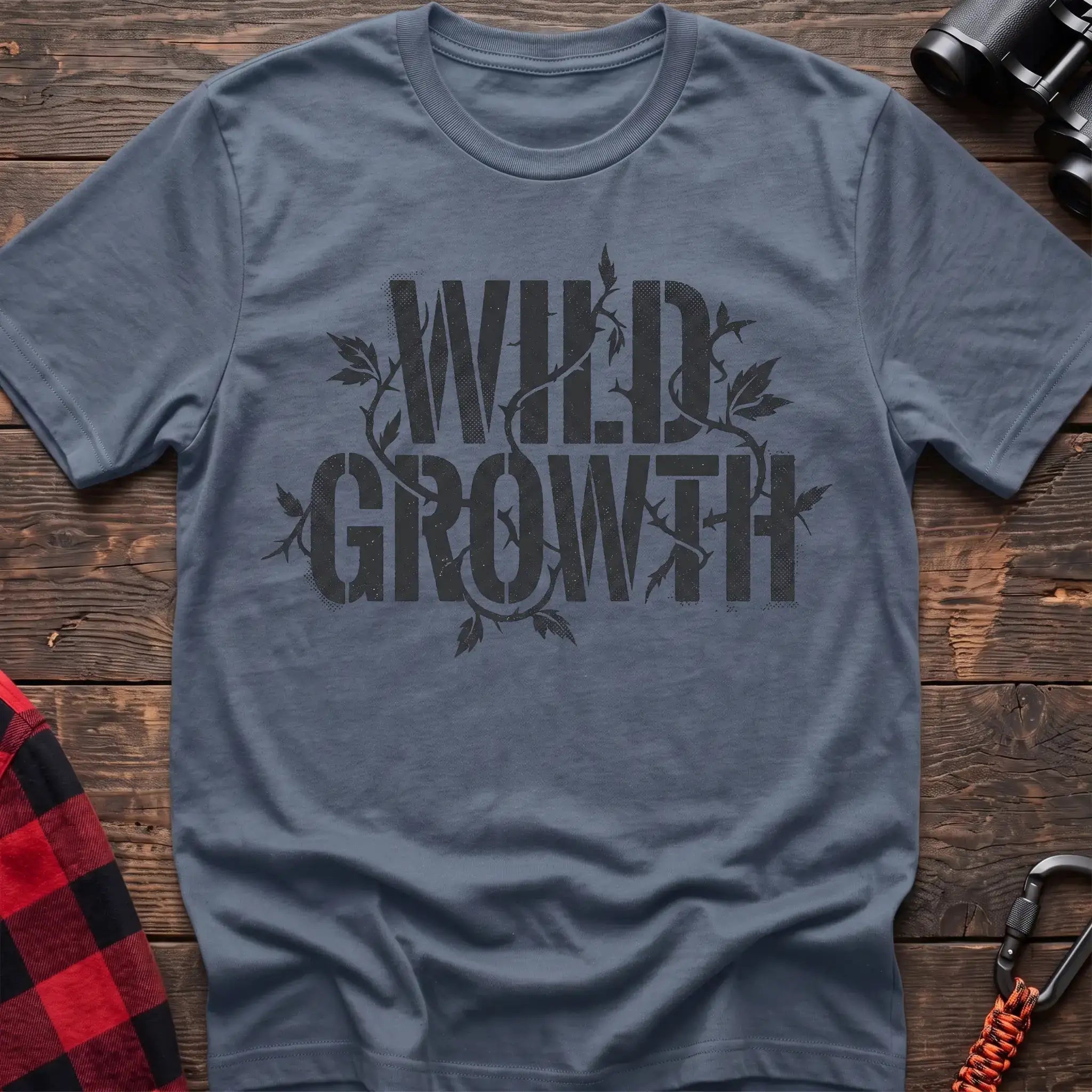 Stone blue t-shirt with dark text reading Wild Growth intertwined with thorny vines and leaves