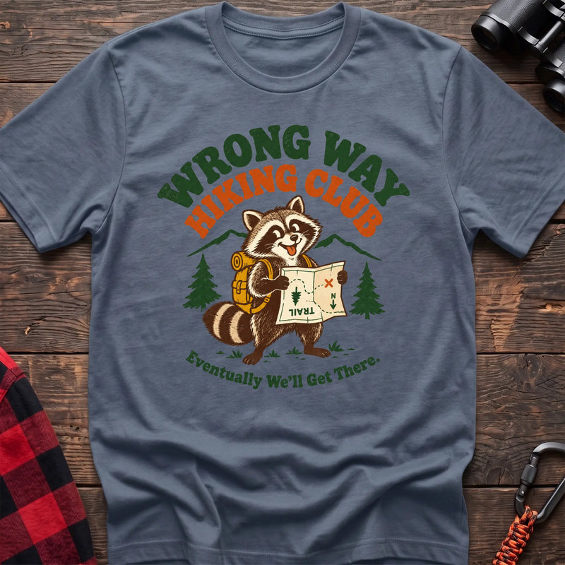 Stone blue cotton t-shirt with a raccoon holding a map graphic and Wrong Way Hiking Club text on rustic wood