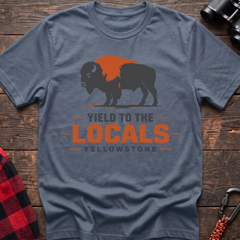 Stone blue cotton t-shirt with a bison graphic and Yield to the Locals Yellowstone text on rustic wood