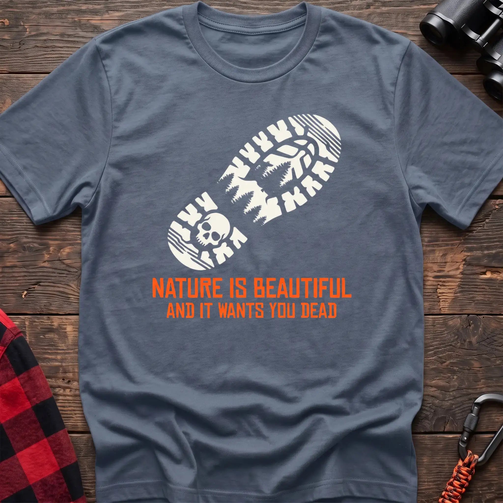 Stone blue t-shirt with white boot print graphic featuring a skull and pine trees, and orange text reading Nature Is Beautiful And It Wants You Dead