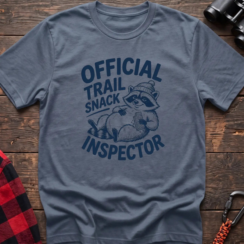 Stone blue t-shirt with cartoon raccoon holding a snack and the text Official Trail Snack Inspector