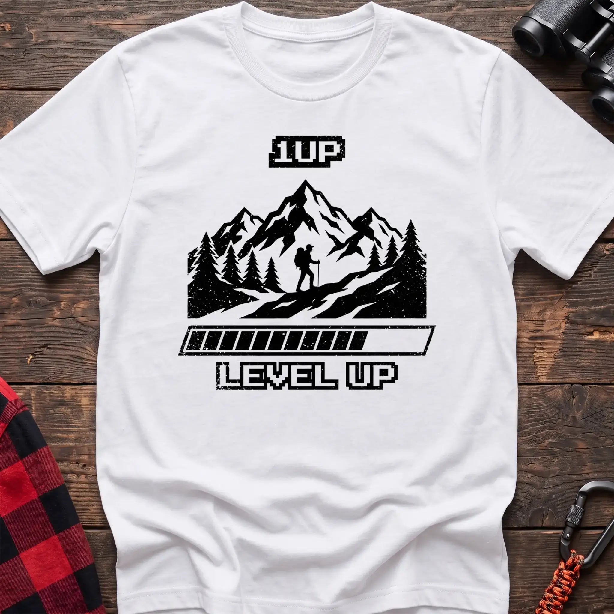 White t-shirt with black graphic of a hiker on a mountain trail under pixel-style 1UP text and a progress bar reading Level Up