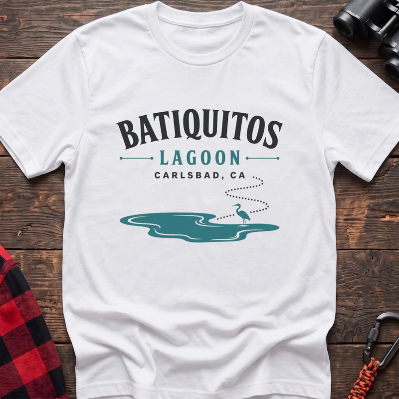 White cotton t-shirt with a heron and lagoon graphic and Batiquitos Lagoon Carlsbad CA text on rustic wood