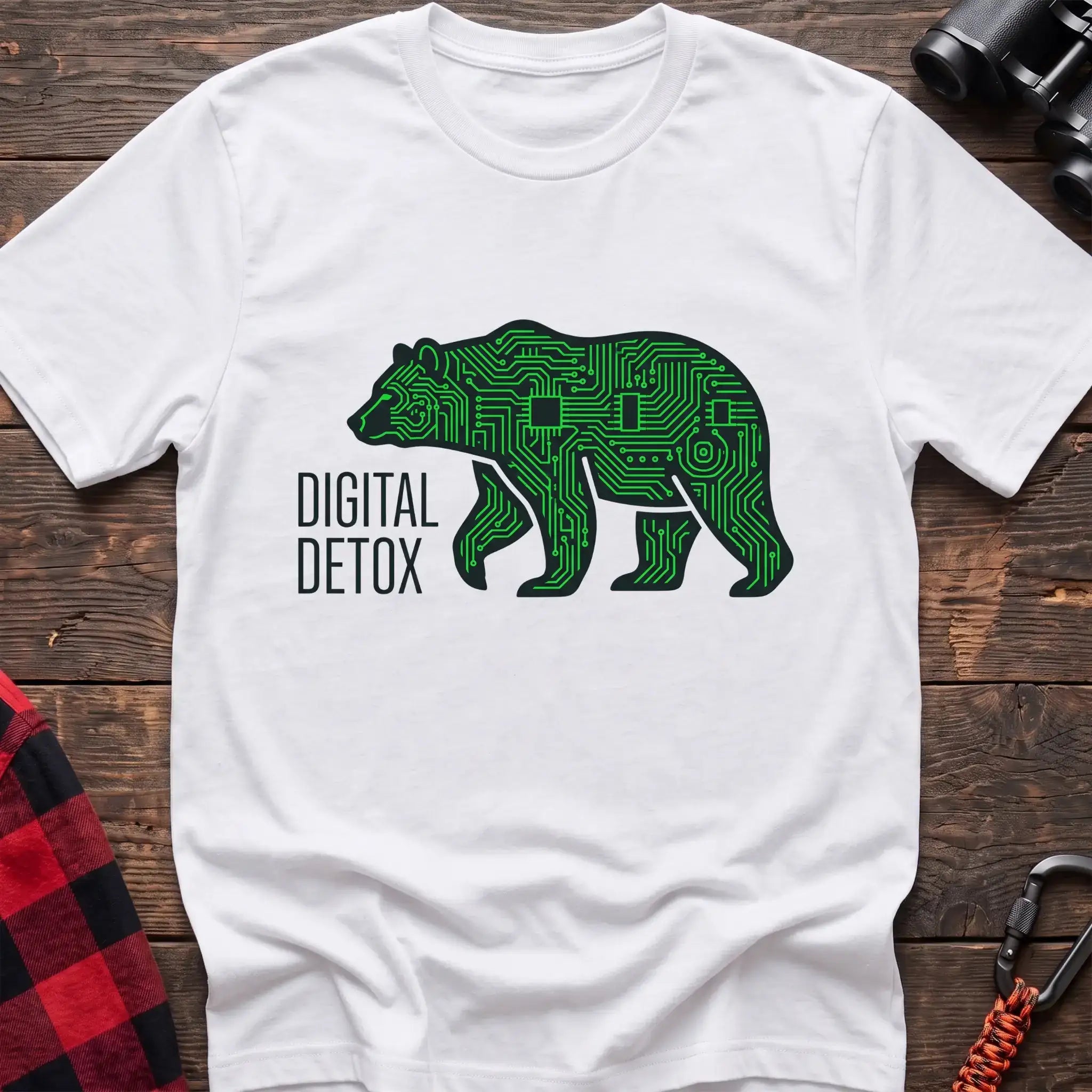 White t-shirt with a neon green circuit-board patterned silhouette of a walking bear, and the text “DIGITAL DETOX” printed to the left of the design, laid flat on a wooden surface.