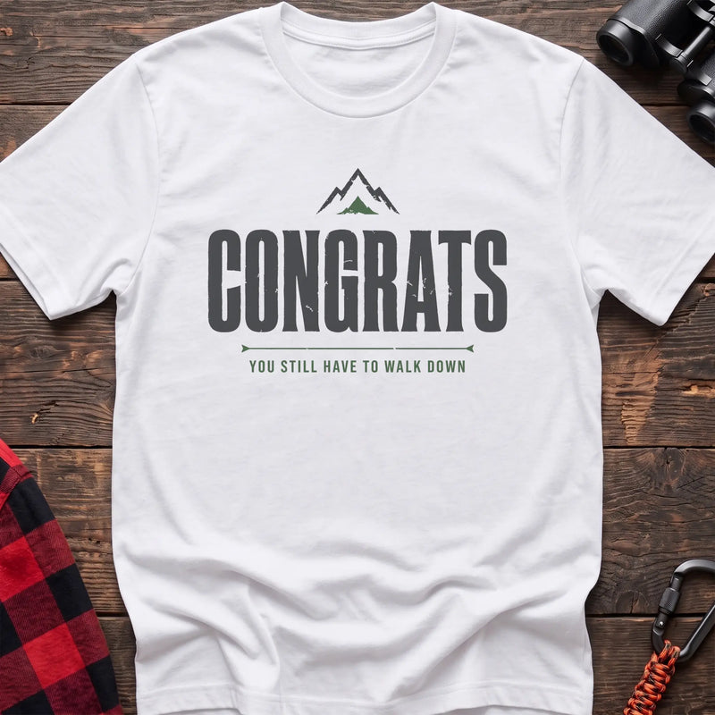 White cotton t-shirt with a mountain graphic and Congrats You Still Have to Walk Down text on rustic wood