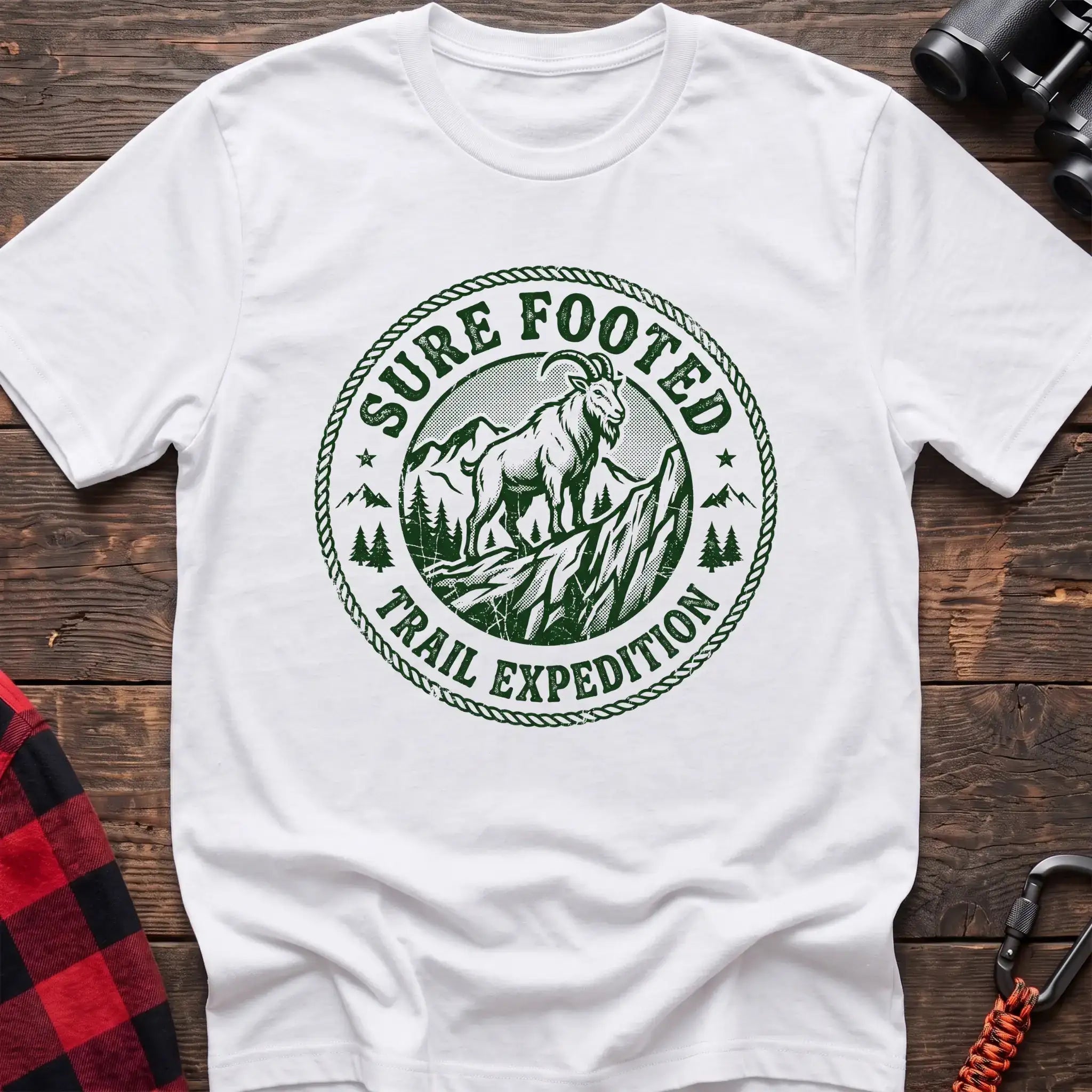 White t-shirt with circular badge graphic of a mountain goat on a rocky peak reading Sure Footed Trail Expedition