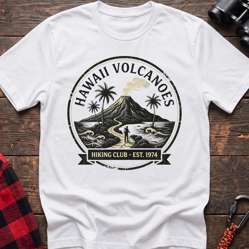 White t-shirt with circular Hawaii Volcanoes badge graphic showing a volcano, palm trees, and a hiker, reading Hiking Club Est 1974
