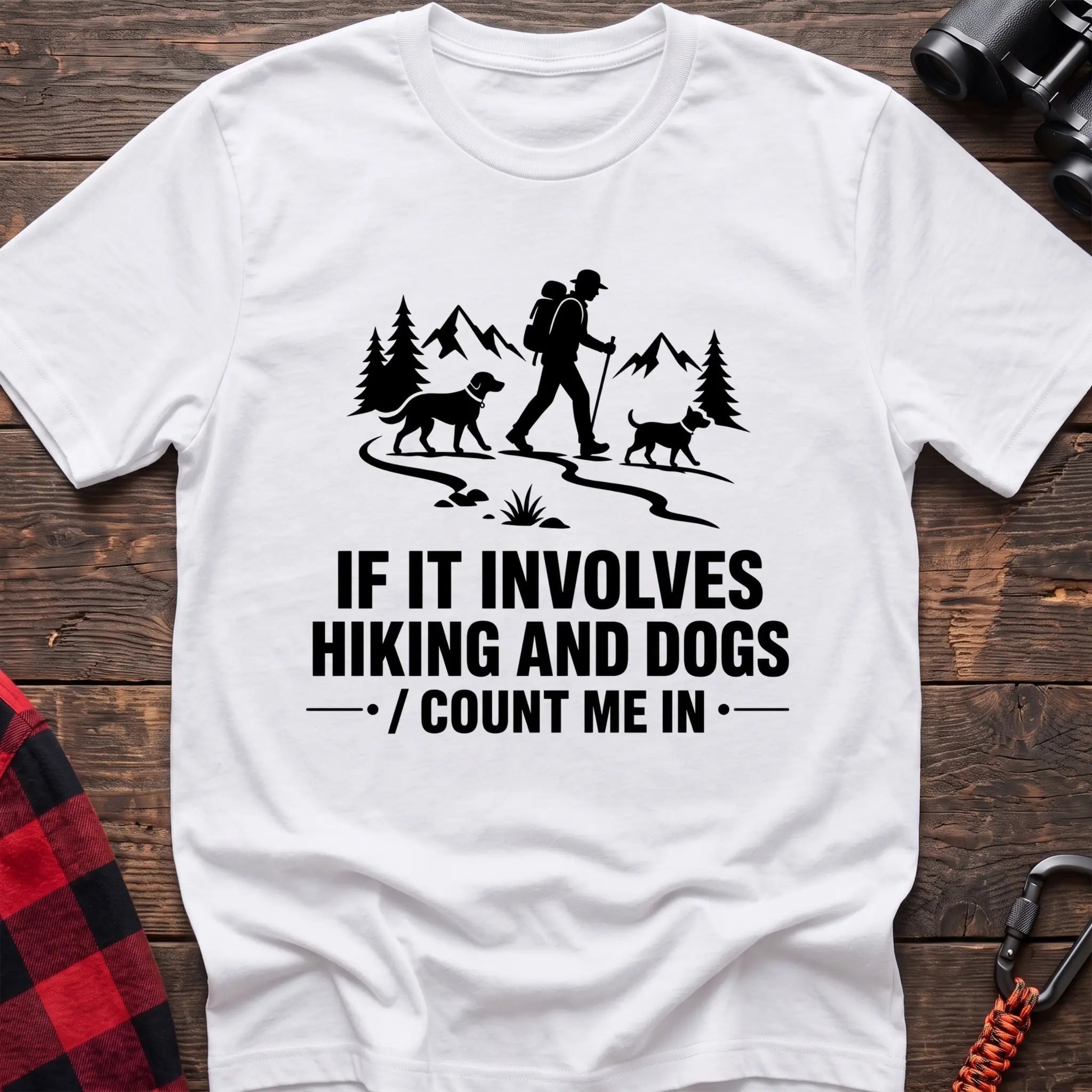 White cotton hiking t-shirt with hiker and two dogs silhouette on a mountain trail and "If it involves hiking and dogs count me in" quote
