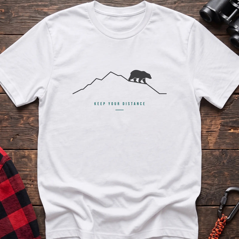 White hiking t-shirt with a line-art mountain, walking bear, and the text “Keep Your Distance”