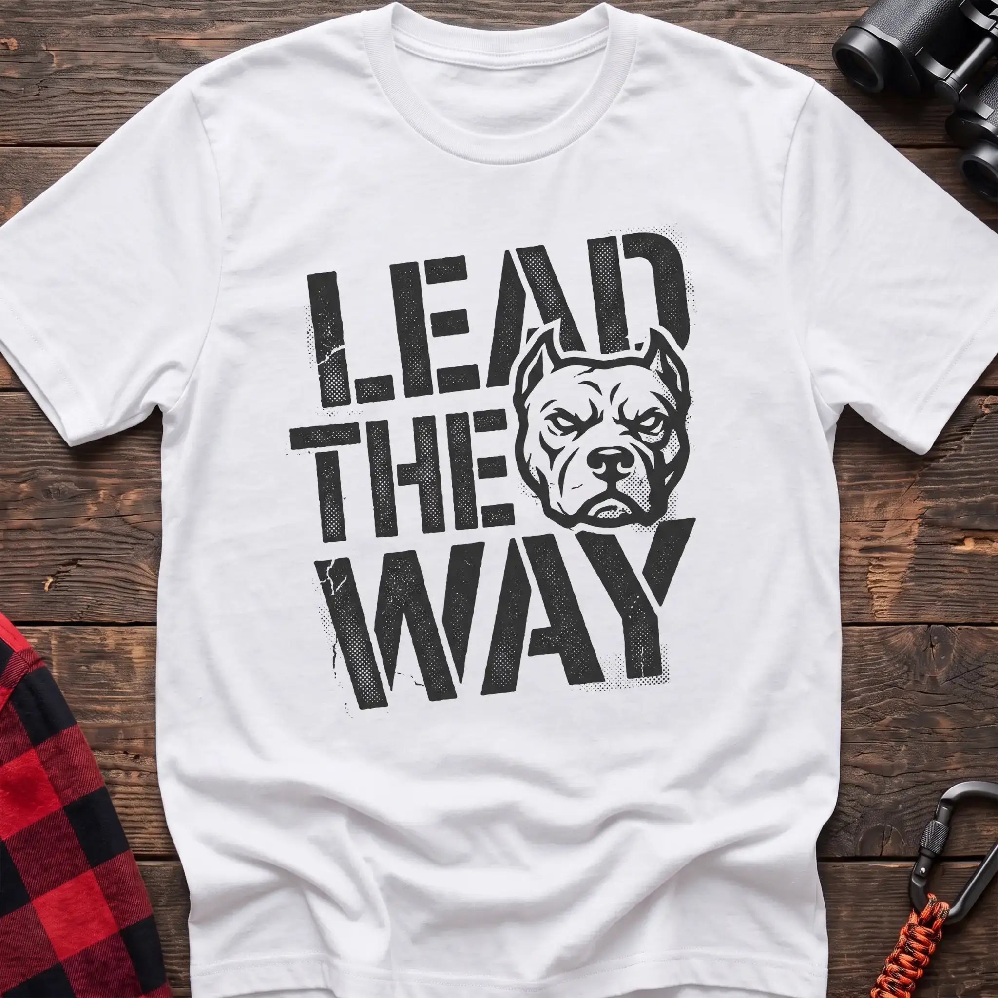 White t-shirt with a distressed graphic of a stern pit bull head integrated into the bold text “LEAD THE WAY,” laid flat on a wooden surface.