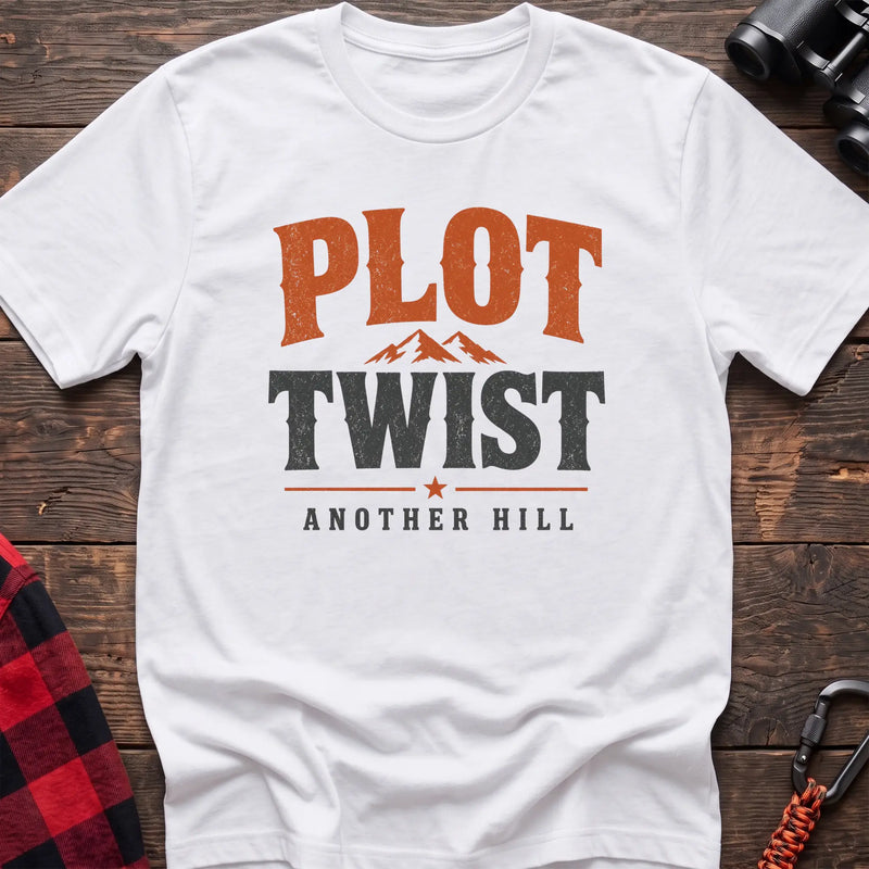 White cotton t-shirt with a mountain graphic and Plot Twist Another Hill text on rustic wood