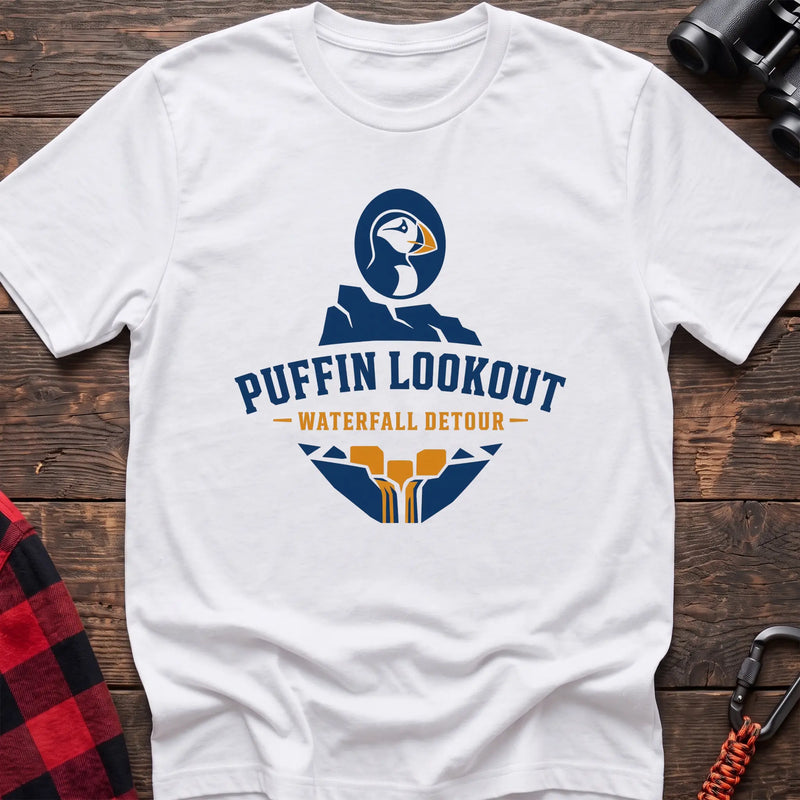 White cotton t-shirt with a puffin and waterfall graphic and Puffin Lookout Waterfall Detour text on rustic wood