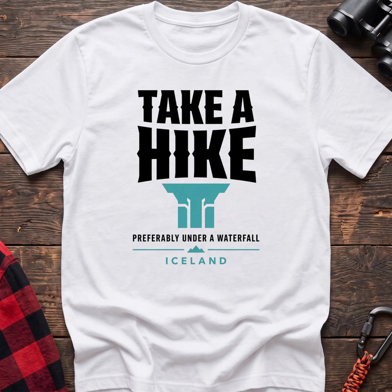 White cotton t-shirt with a waterfall graphic and Take a Hike Preferably Under a Waterfall Iceland text on rustic wood